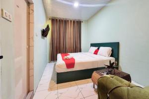 a bedroom with a bed and a couch in a room at RedDoorz at Ingan Cio Homestay Berastagi in Berastagi