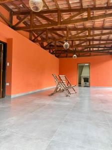 an empty room with orange walls and a wooden chair at Sítio Castelo Branco - Morretes in Morretes