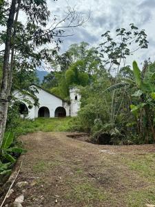 an old white building with two arches in a field at Sítio Castelo Branco - Morretes in Morretes