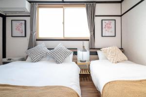 two beds sitting in a room with a window at Biei Sakura Stay in Biei
