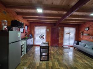 a kitchen and living room with a refrigerator and a couch at Alojamiento Pamela in Coñaripe