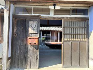 an open door of a wooden building with a sign on it at いなかじかん in Yasuda