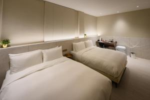 a hotel room with two beds with white sheets at Mr Petter in Taichung