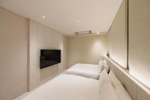 a bedroom with two beds and a tv on the wall at Mr Petter in Taichung