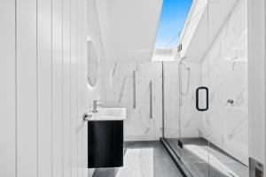 a white bathroom with a sink and a mirror at 44b Scarborough Terrace in Hanmer Springs +12 photos