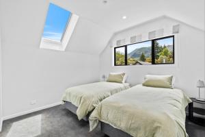 two beds in a white room with a window at 44b Scarborough Terrace in Hanmer Springs