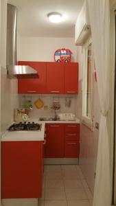 una cocina roja con armarios rojos y fregadero en Cristina' s flat, en Misano Adriatico 17 fotos más