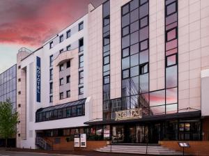 a building with a sign on the front of it at Novotel Paris Suresnes Longchamp in Suresnes