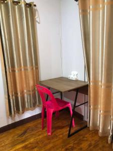 a pink chair sitting next to a small table with curtains at Kohpu garden in Ban Klang