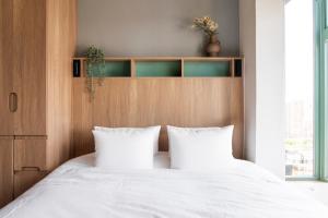 a bedroom with a white bed with two pillows at Weave Studios - Olympic in Hong Kong