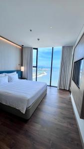a bedroom with a large bed and large windows at Executive Bay View A La Carte Hạ Long in Ha Long
