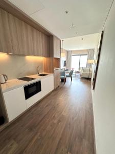 a kitchen with white cabinets and a living room at Executive Bay View A La Carte Hạ Long in Ha Long
