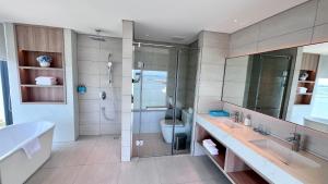 a bathroom with a shower and two sinks and a toilet at Executive Bay View A La Carte Hạ Long in Ha Long +15 photos
