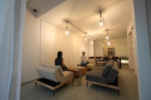 two people sitting in a room with chairs and a table at TomaReno Beppu-Kitahama in Beppu