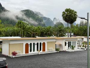 a building with palm trees and mountains in the background at Farinda Resort in Phangnga