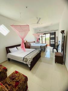 a bedroom with two beds and a room with two chairs at Hotel Meer in Ambalangoda