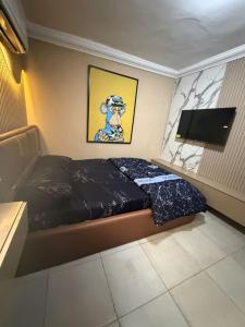ein Schlafzimmer mit Bett und Flachbildfernseher in der Unterkunft Royal Max in Ikeja
