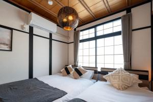 two beds in a room with a window at Biei Sakura Stay in Biei