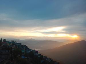 a view of a city with the sunset in the background at Bluemoon stay in Darjeeling