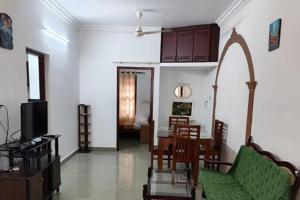 a living room with a table and chairs and a television at Agapi Homestay in Cochin