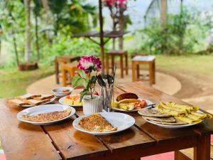 a wooden table with plates of food on it at Wow Field Homestay in Ella