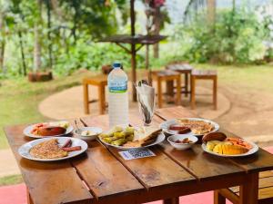 a wooden table with plates of food and a bottle of water at Wow Field Homestay in Ella +39 photos