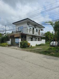 a white house with a balcony on a street at Mollucan Suite Moalboal in Moalboal