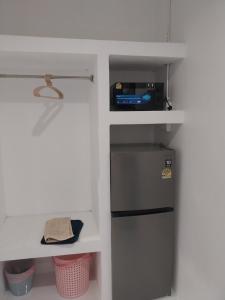 a small kitchen with a refrigerator and a shelf at Koh Tao Townhouse in Ko Tao