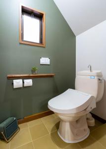 a bathroom with a white toilet and a window at ゲストハウス あぽわん 貸切宿無料駐車場 in Mitoyo