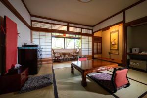 a living room with a table and a dining room at Bessou Konjakuan in Yufu