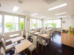 a dining room with tables and chairs and windows at Hotel Mystays Nayoro in Nayoro
