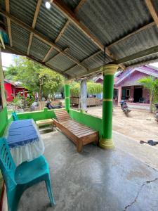 a patio with a bench and a table and green columns at Hatiku Guesthouse in Bunaken