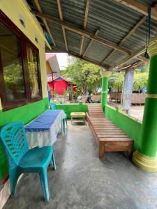 a patio with a table and chairs and a bench at Hatiku Guesthouse in Bunaken