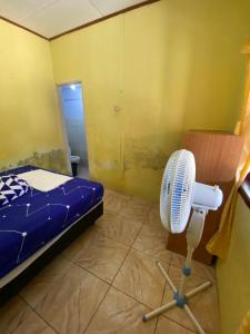 a room with a bed and a fan in it at Hatiku Guesthouse in Bunaken