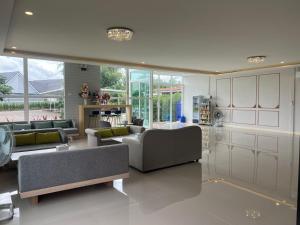 a living room with couches and tables and windows at เพาะสุข กู๊ดดรีม in Ban Wang Hu Kwang
