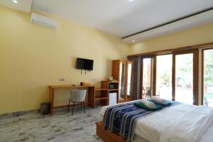 a bedroom with a bed and a desk and a television at Salili Resort in Gili Islands