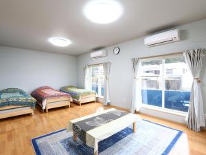 a living room with two beds and a table at Guesthouse&Café Deep in Kōzushima