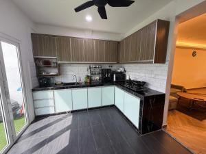 a kitchen with white cabinets and a ceiling fan at Ujang Guest House in Batu Kikir