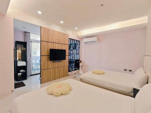 a bedroom with two beds and a television in it at Kinmen Harved B&B in Jinhu