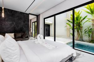a bedroom with a white bed and a swimming pool at Anoya Boutique Villa in Kerobokan +54 photos
