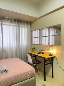 a bedroom with a bed and a desk with a laptop at Avida Tower 2 in Davao City