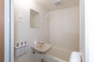 a white bathroom with a sink and a mirror at Suncity Hakata in Hakata