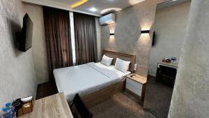 a small hotel room with a bed and a table at Chinor Hotel Fergana in Fergana
