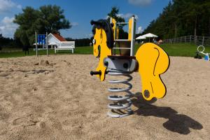 a playground with a yellow play equipment in the sand at Apartamenty Szelągówka in Sorkwity