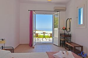 a bedroom with a door open to a patio with a table at Sarakiniko Rooms in Adamantas