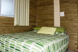 a bedroom with a bed with a wooden wall at Morada Manga Rosa Pousada in Florianópolis
