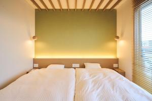 a bedroom with two beds and a green wall at Long Vacation Resort in Fukuoka