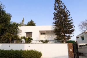 a white house with a tree in front of it at Comfort Lodge in Karachi