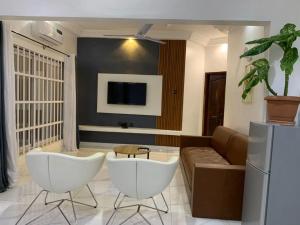 a living room with two white chairs and a couch at Deux chambres salon in Adjarra
