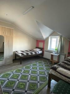 a attic room with two beds and a rug at Snow Leopard Hostel in Karakol